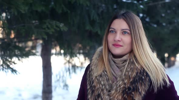 A Beautiful Fashionable Girl Walks Through a Winter Park with a Good Mood and Smiles Beautifully