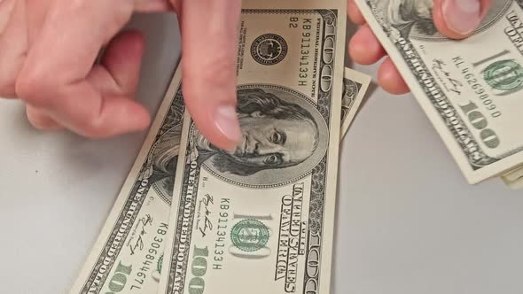 Male Hands Counting Old Hundred Dollar Banknotes on a White Table