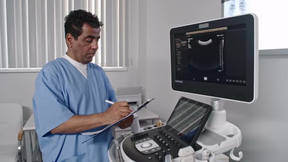 Doctor Writing Down Data from Ultrasound Scan