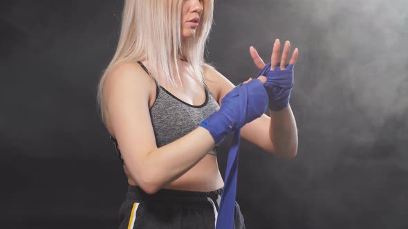 Female Athlete Dressed in Tank Top Wrapping His Fists By Blue Elastic Bandages