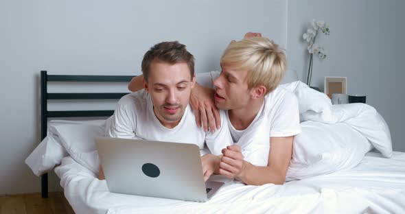 Two Male Gay Couple Using Laptop Computer for Video Calling Talking Distantly with Friends