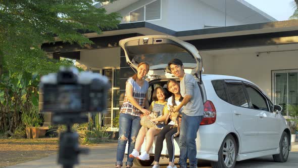 Happy family sit on the car and take a photo together