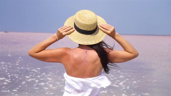 Woman in Hat Walk on a Pink Salt Lake on a Sunny Summer Day.