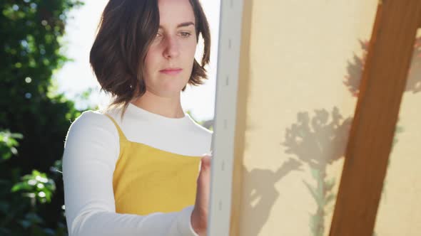 Caucasian woman with brown hair painting in sunny garden