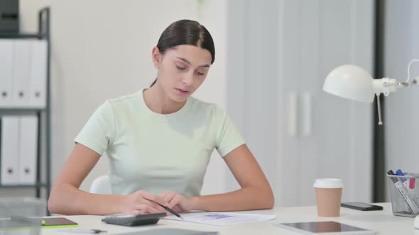 Woman Using Calculator for Work on Documents