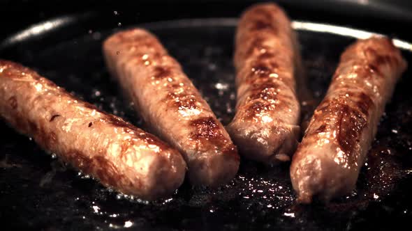 Super Slow Motion Sausages are Fried in a Frying Pan with Splashes of Oil