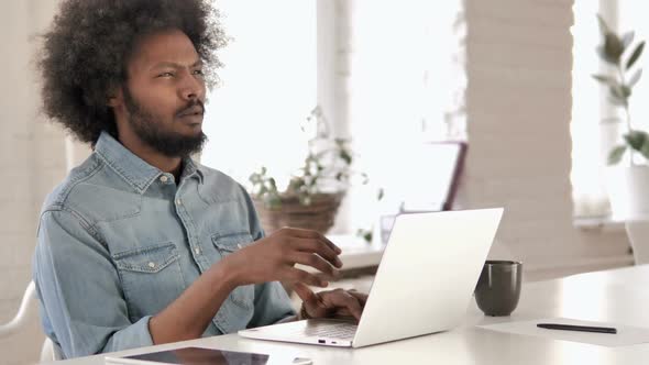 Pensive Creative African Man Thinking and Working on Laptop