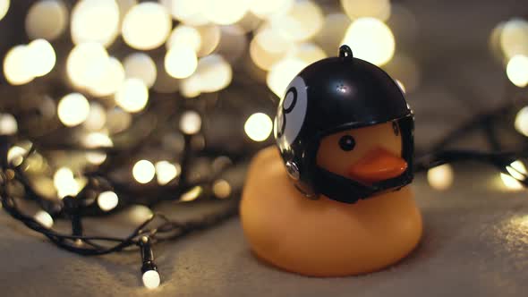 Closeup Shot of Rubber Duck in Hand Made Motorcycle Helmet on Background of Christmas Garland