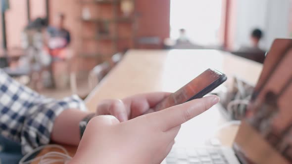 Freelancer Asian woman using smartphone with laptop online shopping in coffee shop