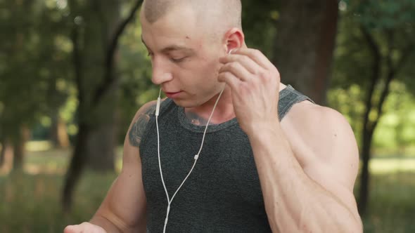 Young Man Chooses Music on Smartphone Before Jogging