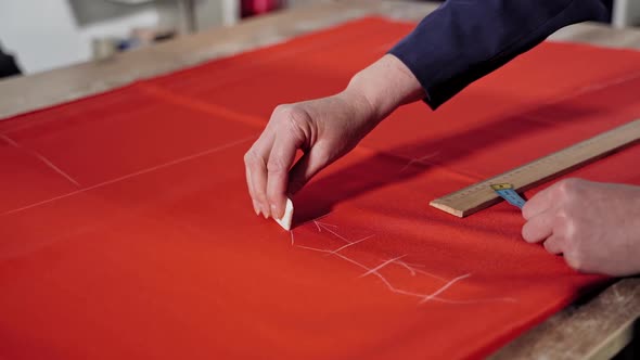 Seamstress working with pattern. View of seamstress measuring the material with a tape