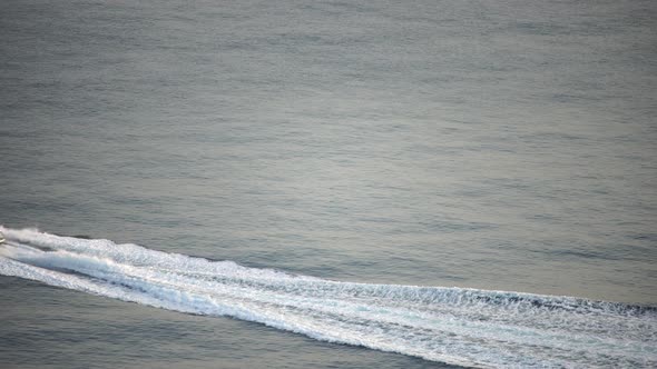 Speedboat Sailing Fast in a Calm Sea on Background of Sea Landscape with Rocky Coastline