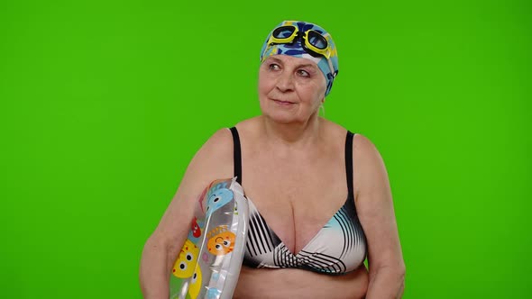 Elderly Woman Tourist in Swimsuit Bra Swim Goggles with Swimming Ring Looking Around on Chroma Key