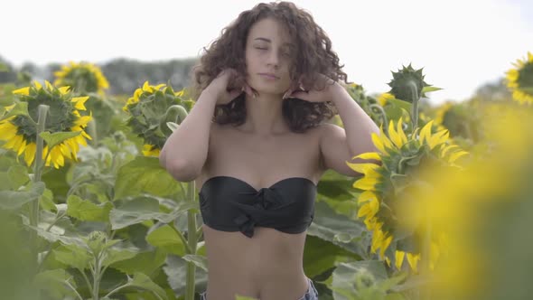 Portrait of a Beautiful Curly Girl in Black Bra Posing and Touching Her Hair Standing