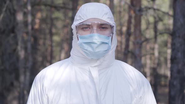 Portrait of Young Caucasian Man in Protective White Clothing, Eyeglasses and Face Mask Standing in