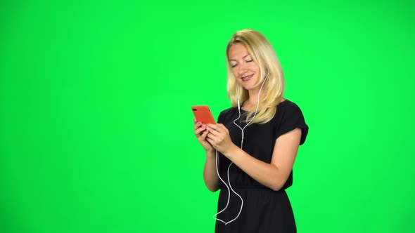 Blonde Girl Goes in Headphones and Texting with Smartphone. Chroma Key. Slow Motion