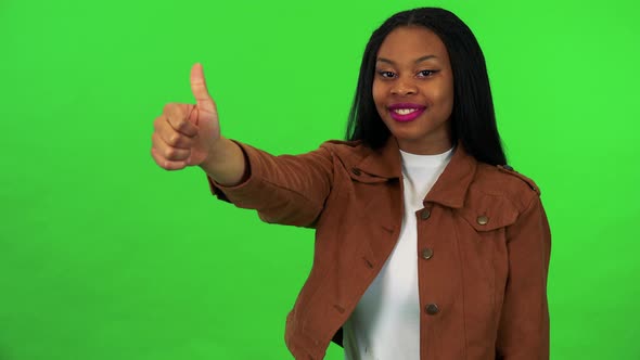 A Young Black Woman Smiles and Shows a Thumb Up To the Camera - Green Screen Studio