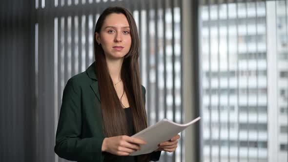 Young woman, office worker looks confidently with a smile at the camera