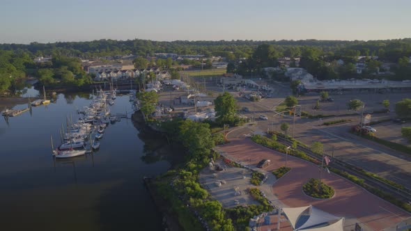 Aerial Pan of a Small Park by the Water and Boats Docked at a Marina