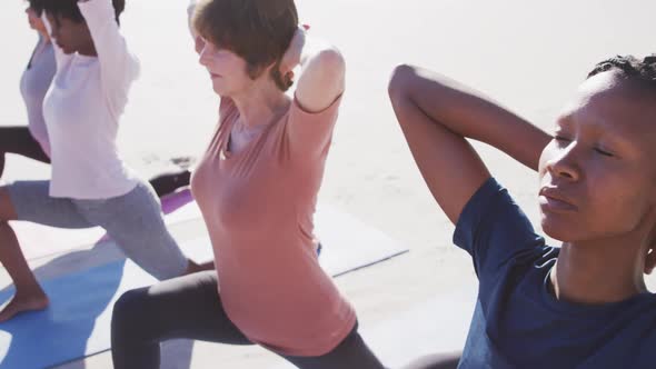 Multi-ethnic group of women doing yoga position on the beach and blue sky background