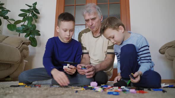 Two little brothers and grandfathers are sitting on the floor