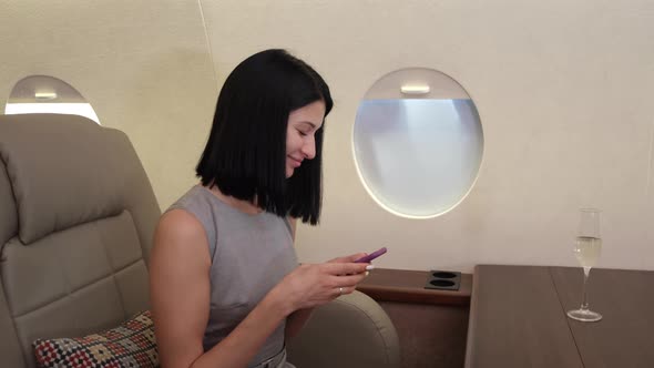 Successful businesswoman working on Smartphone while traveling by private plane