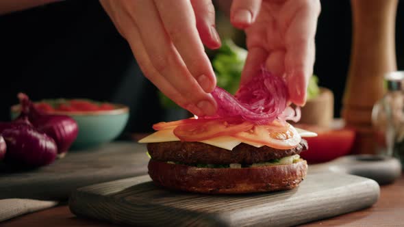 Chef Cooking Burger Putting Onion on Sliced Tomatoes Closeup Making Sandwich Fast Food Concept