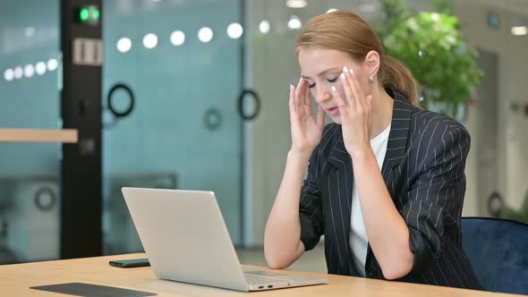 Stressed Businesswoman with Laptop Having Headache in Office 