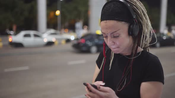 Young Attractive Woman with Dreadlocks Use Smartphone Listening Music on Headphones