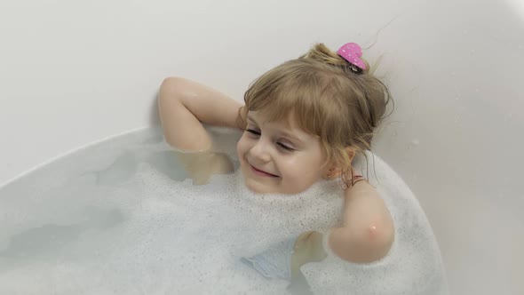 Cute Blonde Girl Takes a Bath in Swimwear. Little Child, 4 Years Old. Hygiene