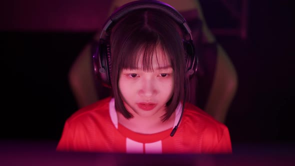 Portrait of an Asian Female Gamer in Headphones Plays a Video Game Cyber Sportsman at the Game