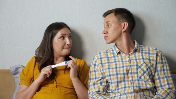 Woman Shows a Man the Result of a Pregnancy Test While Sitting in Bed Surprise Thoughtfulness
