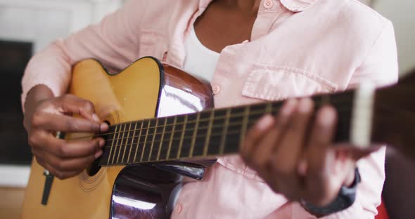 Mid section of african american woman playing guitar at home