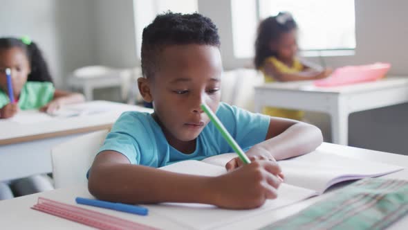 Video of focused african american boy doing lessons in classroom