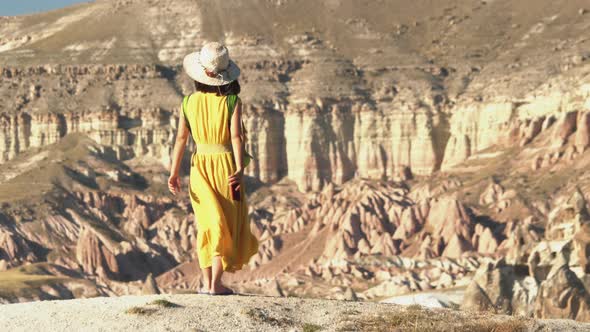 Woman in Yellow Dress and Hat is Watching the Scenic View of Stunning Sandstone Hoodoos Landscape