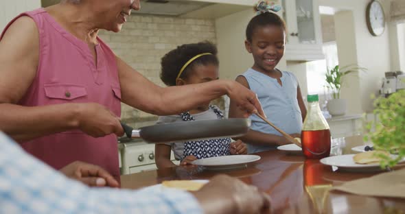 Happy african american grandparents with granddaughters having breakfast and talking