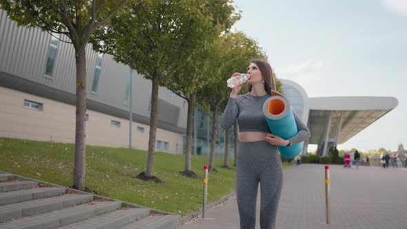 Young Woman Running Drink Water After Workout Outdoors in the City