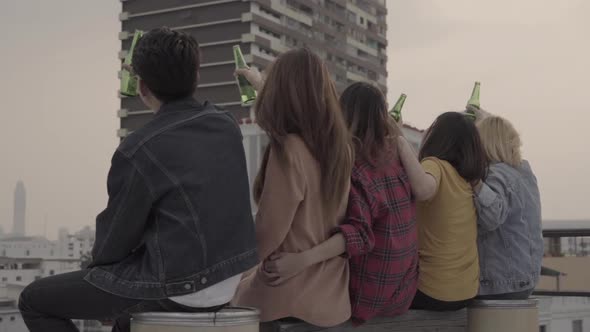 Group of young asian people dancing and raising their arms up played sunset on rooftop hanging out.