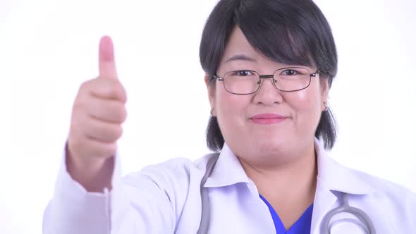Face of Happy Overweight Asian Woman Doctor Giving Thumbs Up