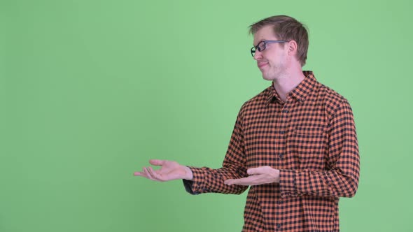 Stressed Young Hipster Man Showing Something and Giving Thumbs Down