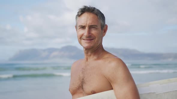 Portrait of man on beach with surfboard