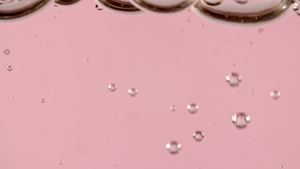 Macro Shot of Air Bubbles in Water Rising Up on Light Pink Background