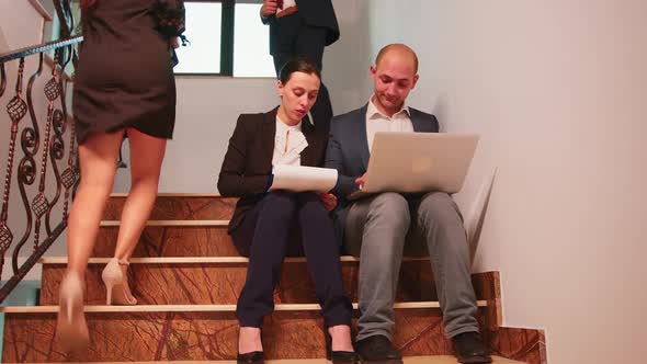 Business People Analysing Reports Sitting on Stairs
