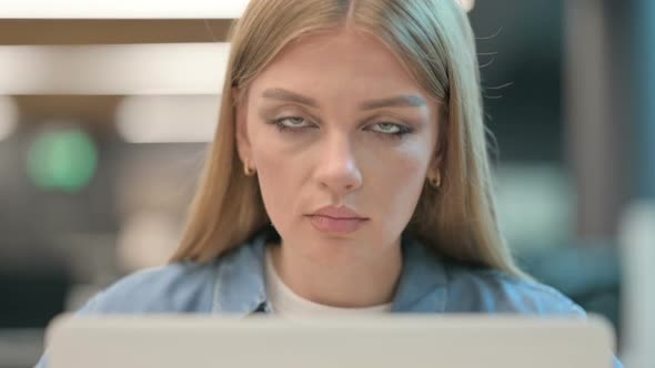 Close Up of Woman Looking at Camera While Using Laptop