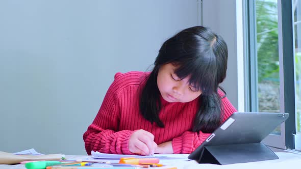 Asian girl sitting at home coloring pictures.