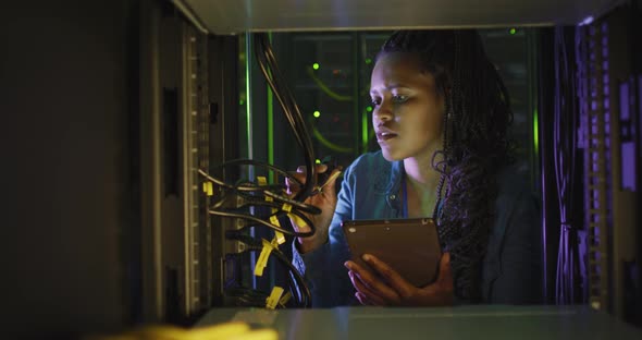 African american female computer technician using tablet working in business server room