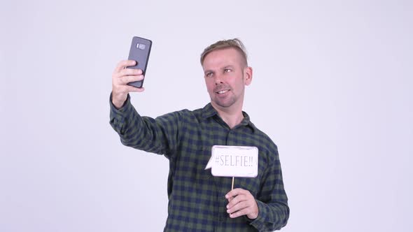 Portrait of Happy Blonde Hipster Man Taking Selfie with Paper Sign