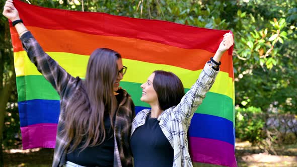 Lesbian Couple From the Lgtb Community Walking in the Park with the Rainbow Flag While Hugging