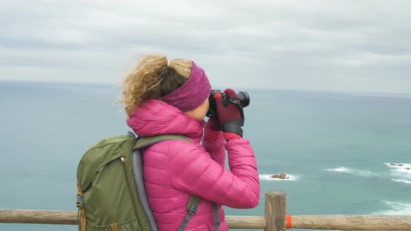Tourist in Pink Jacket Takes Picture of Ocean on Nasty Day