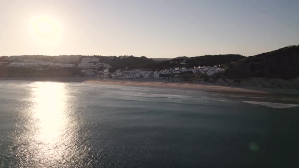 Sun reflecting in the ocean while flying towards Salema beach in Portugal